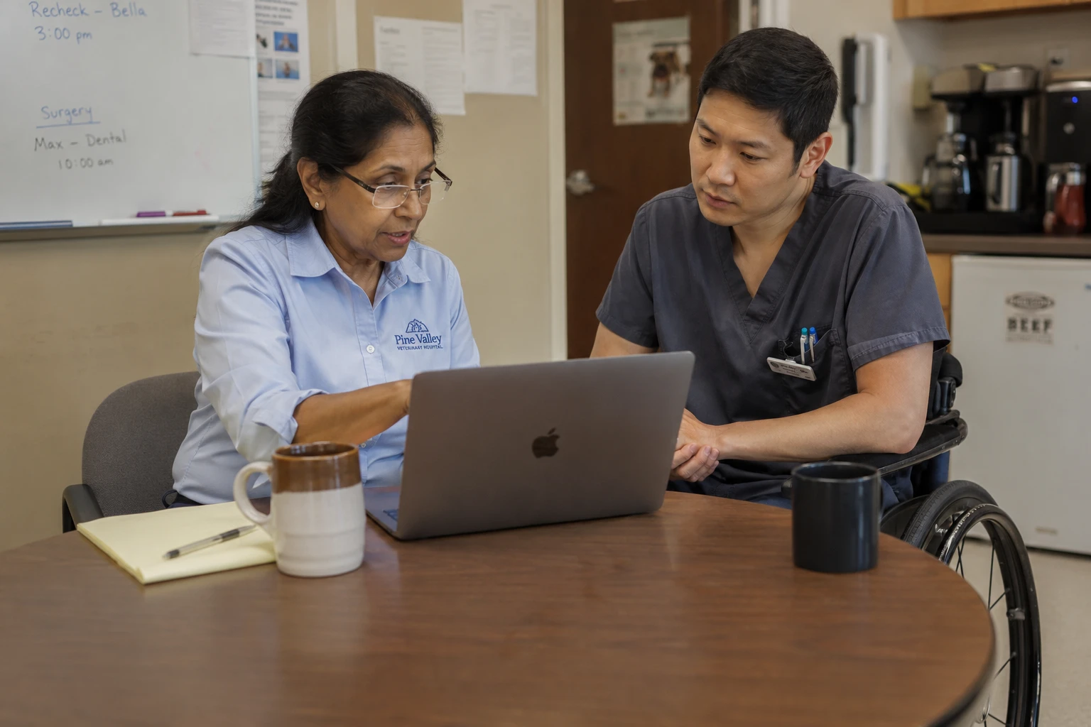 Practice owner and technician comparing veterinary software vendor options in a hospital break room meeting