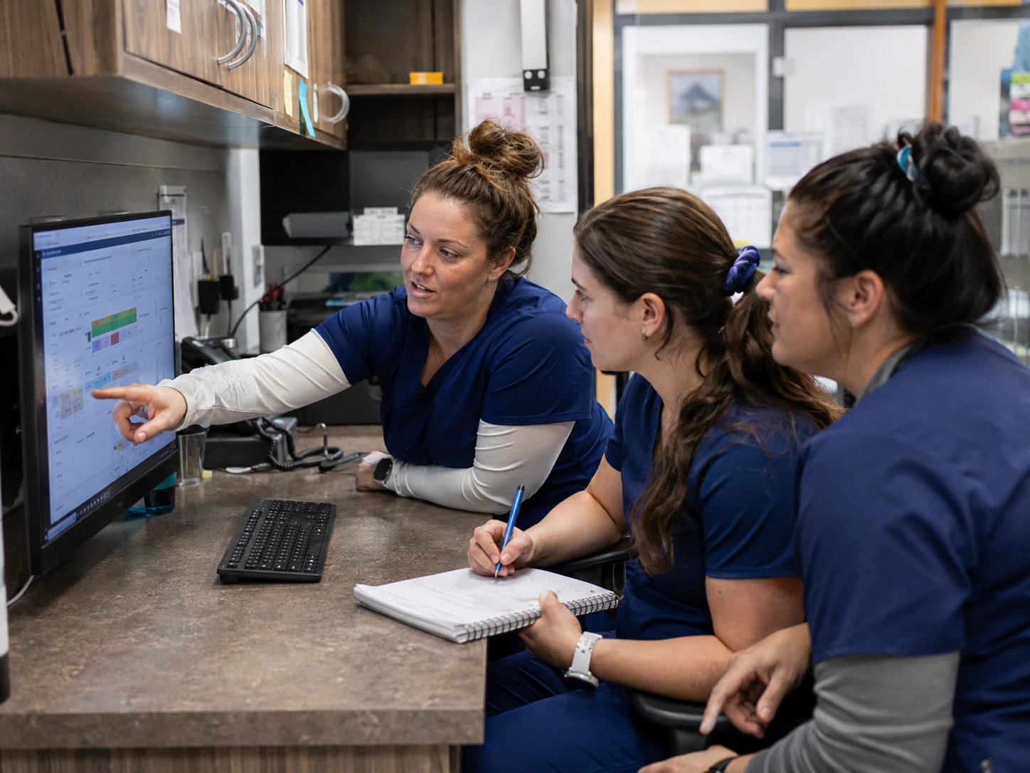 Veterinary team gathered around a computer during client communication software onboarding and training