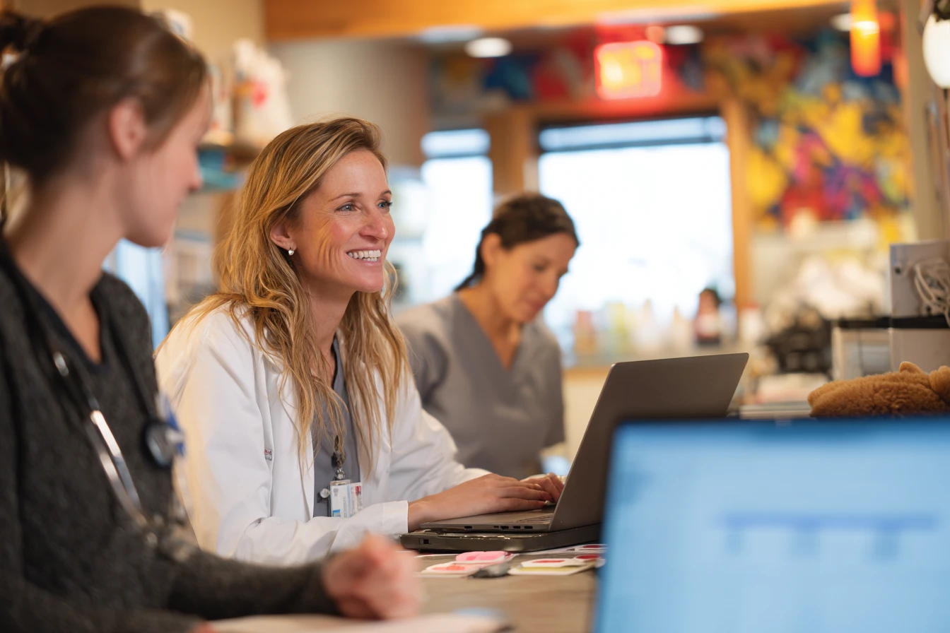 Trainer guiding veterinary staff through an onboarding plan on a laptop with the project schedule blurred